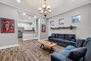 A modern living room with a gray sofa, a wooden coffee table, and a chandelier.