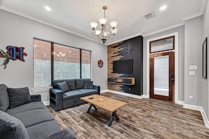 A modern living room with a sofa, coffee table, TV, and a brick wall.