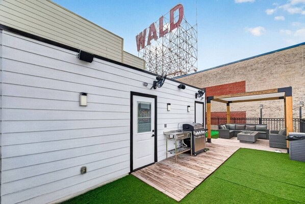 A building with a white exterior, a grill area, and a seating area with a view of the water.
