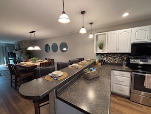 A modern kitchen with a central island, stainless steel appliances, and pendant lighting.