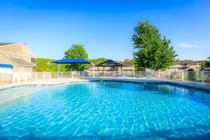A swimming pool with a clear blue water surface, surrounded by a fence, and adjacent to buildings with a covered pavilion. - Waterfront Lake Escape - Pool, Dock, Sunset Views (Osage Beach)