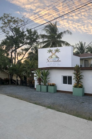 A sign for 'Xanadu Pier Resort Restaurant Bar' with palm trees and a building in the background. - Xanadu Resort Roatan (Sandy Bay)