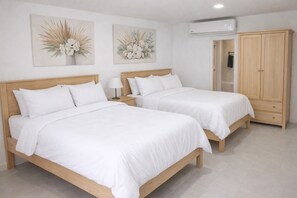 A room with two beds, a wardrobe, and wall-mounted artwork. - Xanadu Resort Roatan (Sandy Bay)