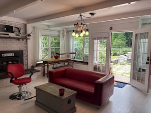 Ein Wohnzimmer mit rotem Sofa, einem Holztisch, einem roten Sessel, einem Kamin und einem Essbereich mit Tisch und Stühlen.