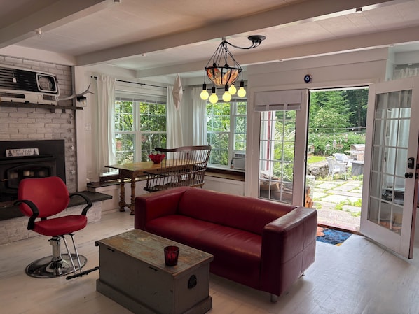 A living room with a red sofa, a wooden coffee table, a red chair, a fireplace, and a dining area with a table and chairs.