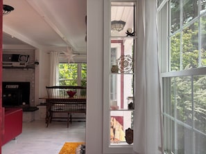 Ein Zimmer mit Kamin, Esstisch und einem Fenster mit Blick auf Bäume.