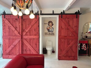 A room with a red sofa, a toilet, and a wall-mounted sink.