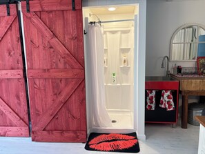 A bathroom with a shower, a sink, and a mirror. - The Tipsy Gypsy - Studio Apartment (Brewster)