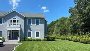 A two-story house with a front porch, a garage, and a well-maintained lawn. - Hamptons Retreat Pool Oasis Modern House (Hampton Bays)