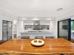 Una cocina moderna con armarios blancos, una isla central y un comedor con mesa de madera y sillas de cuero.