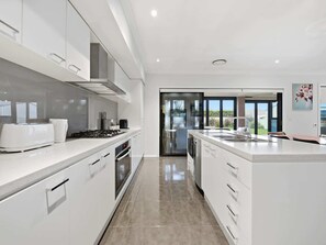 Una cocina moderna con armarios blancos, estufa a gas y una isla grande con pileta.