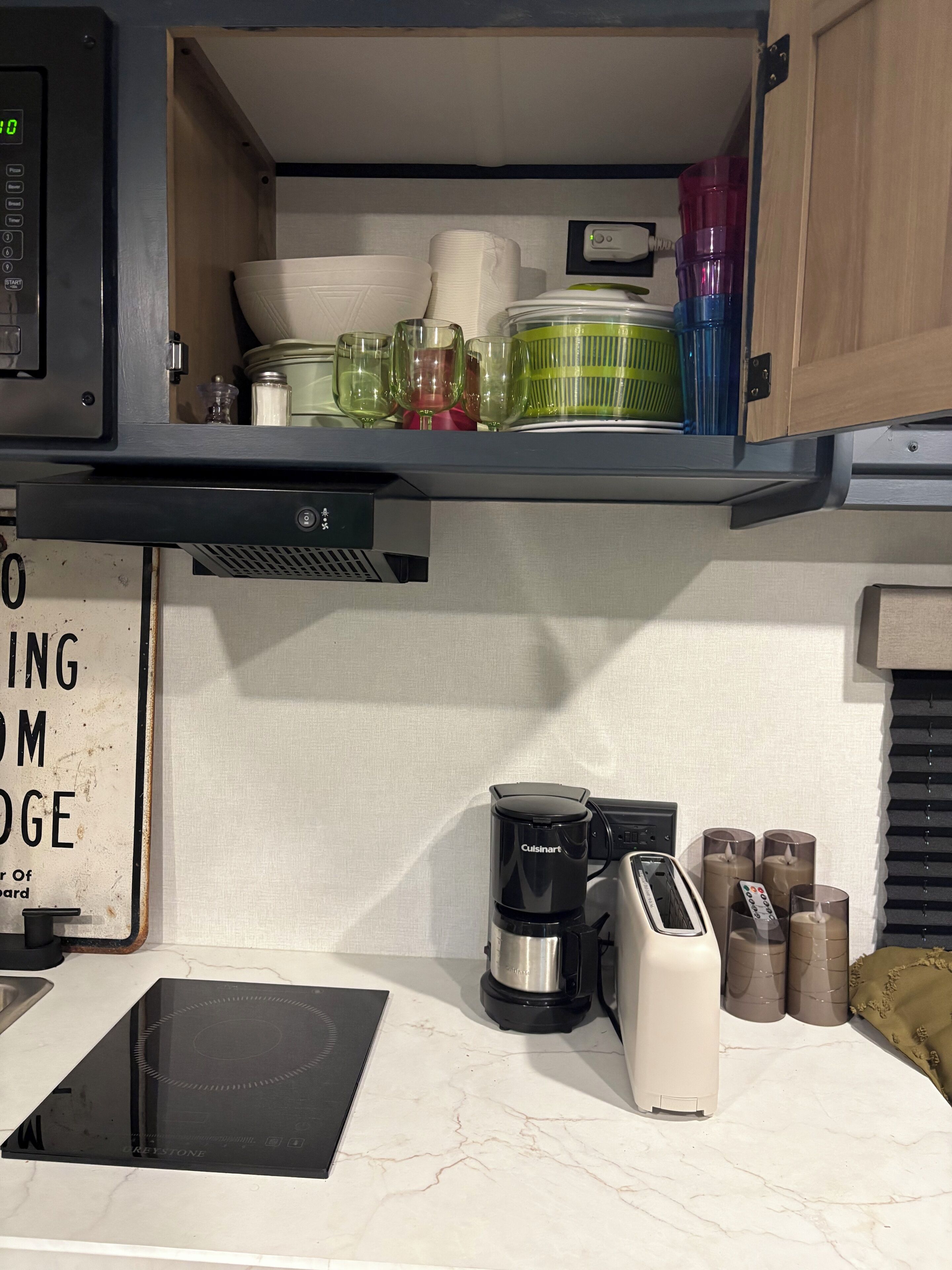 A kitchen with a built-in oven, a coffee maker, a toaster, and a sign on the wall.