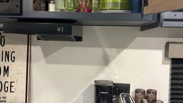 A kitchen with a built-in oven, a coffee maker, a toaster, and a sign on the wall.