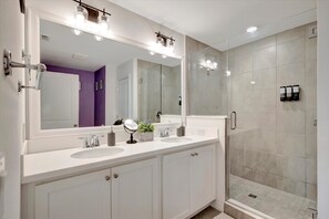 A modern bathroom with a double sink, a large mirror, and a walk-in shower. - Splash Pool Townhome at Festival Resort (Davenport)