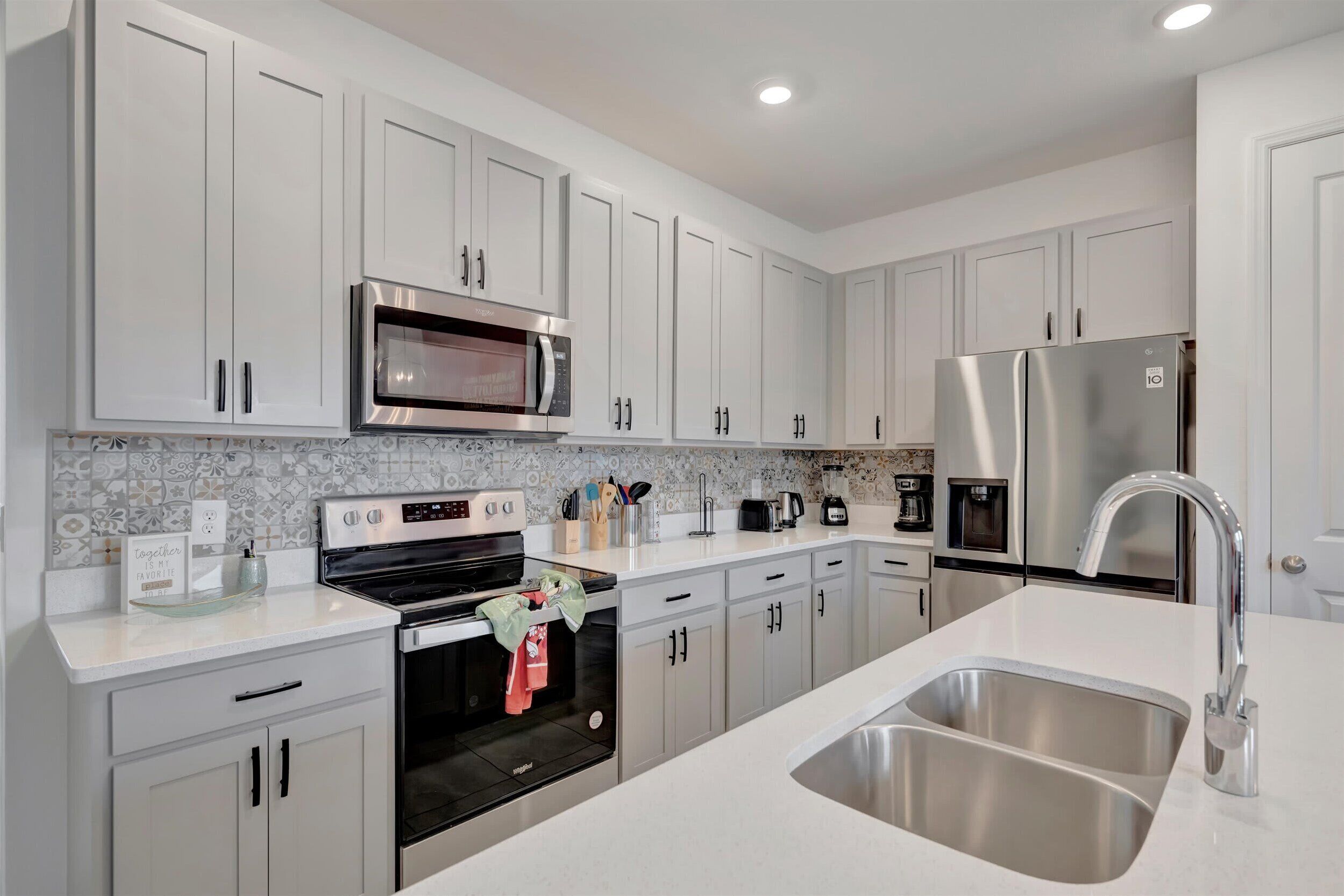 A modern kitchen with white cabinets, stainless steel appliances, and a built-in oven.