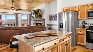 A modern kitchen with granite countertops, stainless steel appliances, wooden cabinets, and a fireplace. - NEW CABIN-Epic Sunsets! Panoramic Views of Blue Ridge and Smokey Mountains! (Murphy)