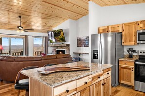 Eine moderne Küche mit Granit Arbeitsplatten, Edelstahlgeräten, Holzschränken und einem Kamin.