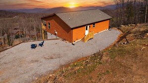 A wooden cabin with a gravel driveway and two chairs. - NEW CABIN-Epic Sunsets! Panoramic Views of Blue Ridge and Smokey Mountains! (Murphy)