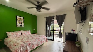 A bedroom with a bed, a ceiling fan, a TV, and a sliding glass door leading to an outdoor area. - Amaizing Place in Sayulita (Sayulita)
