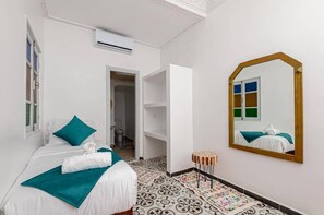 Habitación de hotel con cama, espejo, una mesita y baño visible a través de una puerta abierta.