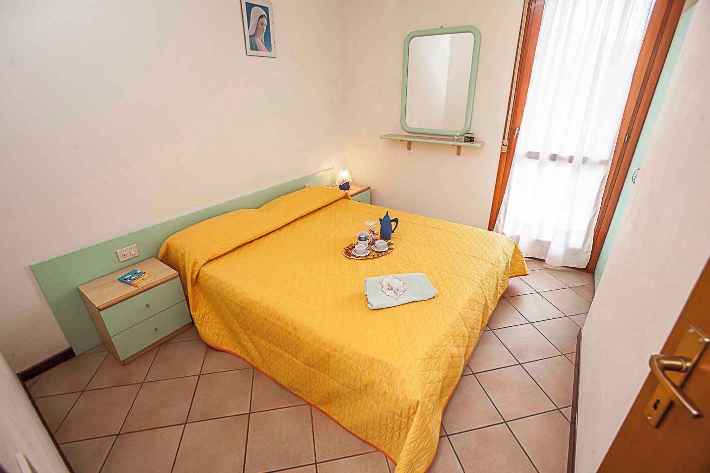 Una camera da letto con un letto, un comodino e uno specchio a parete.