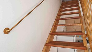 Eine Holztreppe mit Handlauf, weißen Wänden und Holzboden.
