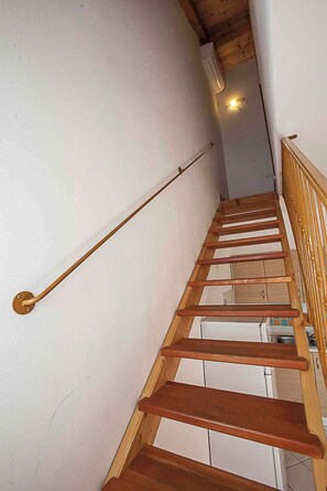 Eine Holztreppe mit Handlauf, weißen Wänden und Holzboden.