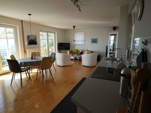 Eine moderne Küche mit Essbereich, Fernseher und großem Fenster.