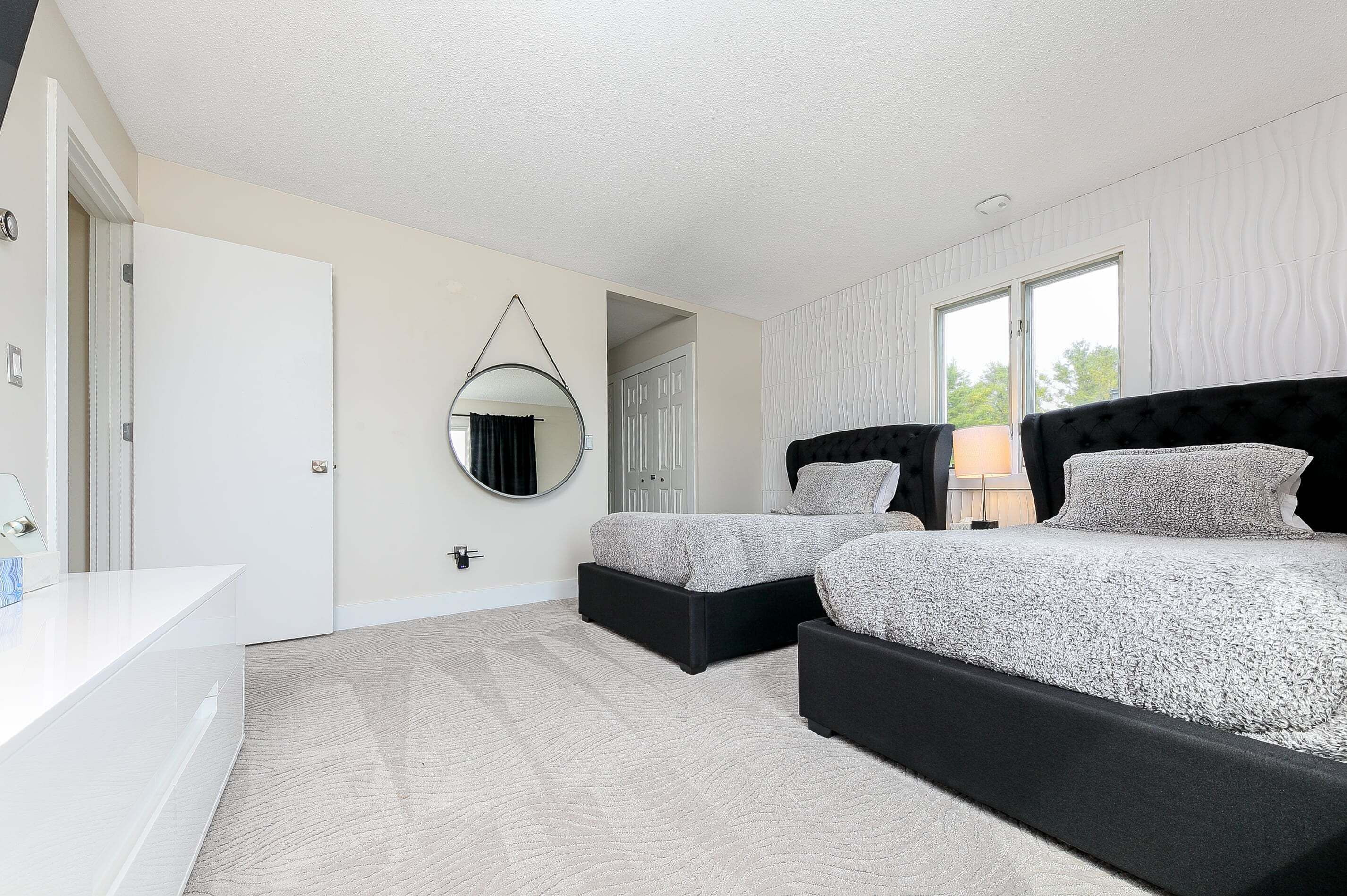 A bedroom with a bed, bedside tables, a mirror, and a door.