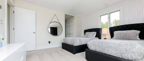 A bedroom with a bed, bedside tables, a mirror, and a door.