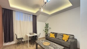 A modern living room with a dining table, sofa, and a ceiling light fixture. - Large 2BR Home • Perfect for Groups (Istanbul)