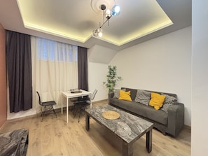 Ein modernes Wohnzimmer mit Esstisch, Sofa und einer Deckenleuchte.