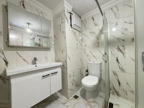 Ein Badezimmer mit einem weißen Waschbecken, einer Toilette und einer Duschkabine.