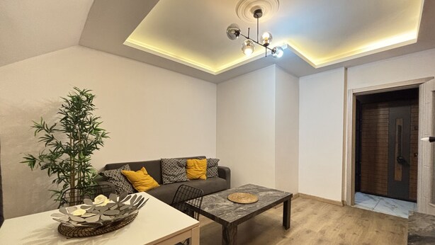 A modern living room with a sofa, coffee table, and a dining area with a plant and decorative bowl. - Large 2BR Home • Perfect for Groups (Istanbul)