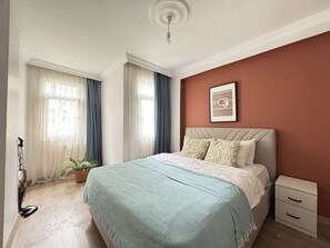 Ein Schlafzimmer mit einem Bett, einem Nachttisch, einem Wandbild und einer Topfpflanze.
