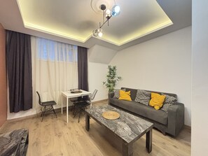 Ein modernes Wohnzimmer mit Esstisch, Sofa und einer Deckenleuchte.