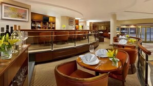 Um saguão de hotel com área de bar, assentos e vista para a rua.