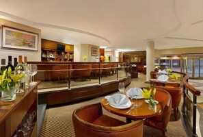 Un hall de hotel con área de bar, asientos y vistas a la calle.