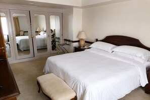 Habitación de hotel con una cama grande, una mesita de noche de madera, una lámpara, un espejo y un armario con espejo.