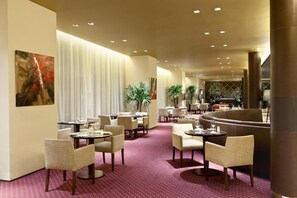 A hotel lobby with dining tables, chairs, a bar area, and a large painting on the wall. - Stylish & Soundproof Room in a Premium Downtown Location | Pet-Friendly (Buenos Aires)