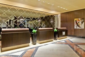Un área de recepción con diseño moderno, que incluye un mostrador, un panel decorativo y un piso con estampado geométrico.