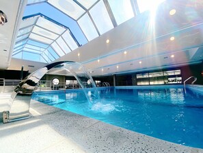 Una piscina interior con techo de cristal, agua cristalina y diseño moderno.