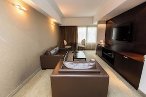 A modern hotel room with a sofa, a small dining table, two chairs, a TV, and a minibar. - Escape to a Tranquil Room Near Puerto Madero Riverfront Dining | Rooftop Pool (Buenos Aires)
