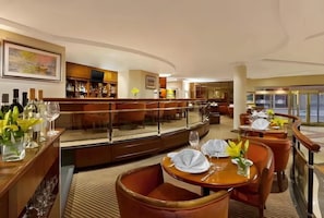 Un hall de hotel con área de bar, asientos y vistas a la calle.