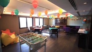 A room with a foosball table, tables, chairs, and colorful balloons. - Upscale King Room in the Heart of Buenos Aires  | Rooftop Pool + Hot Tub (Buenos Aires)