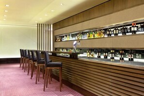 A bar area with multiple chairs, a counter with bottles, and a patterned wall. - Rooftop Pool & Sauna | Near Florida St. & Galerías Pacífico | Pets Allowed (Buenos Aires)