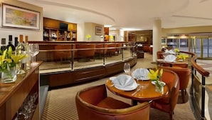Un hall de hotel con área de bar, asientos y vistas a la calle.