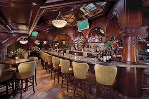 A bar area with wooden furniture, a bar counter, and a television screen.
