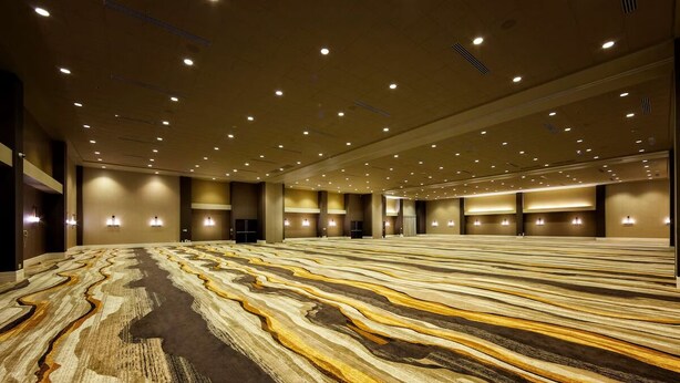 Un hall de hotel espacioso con una alfombra de diseño llamativo e iluminación empotrada.