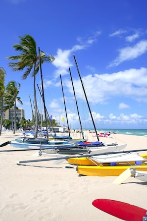 Ein Strand mit mehreren angestuften Booten, Palmen und blauem Himmel.